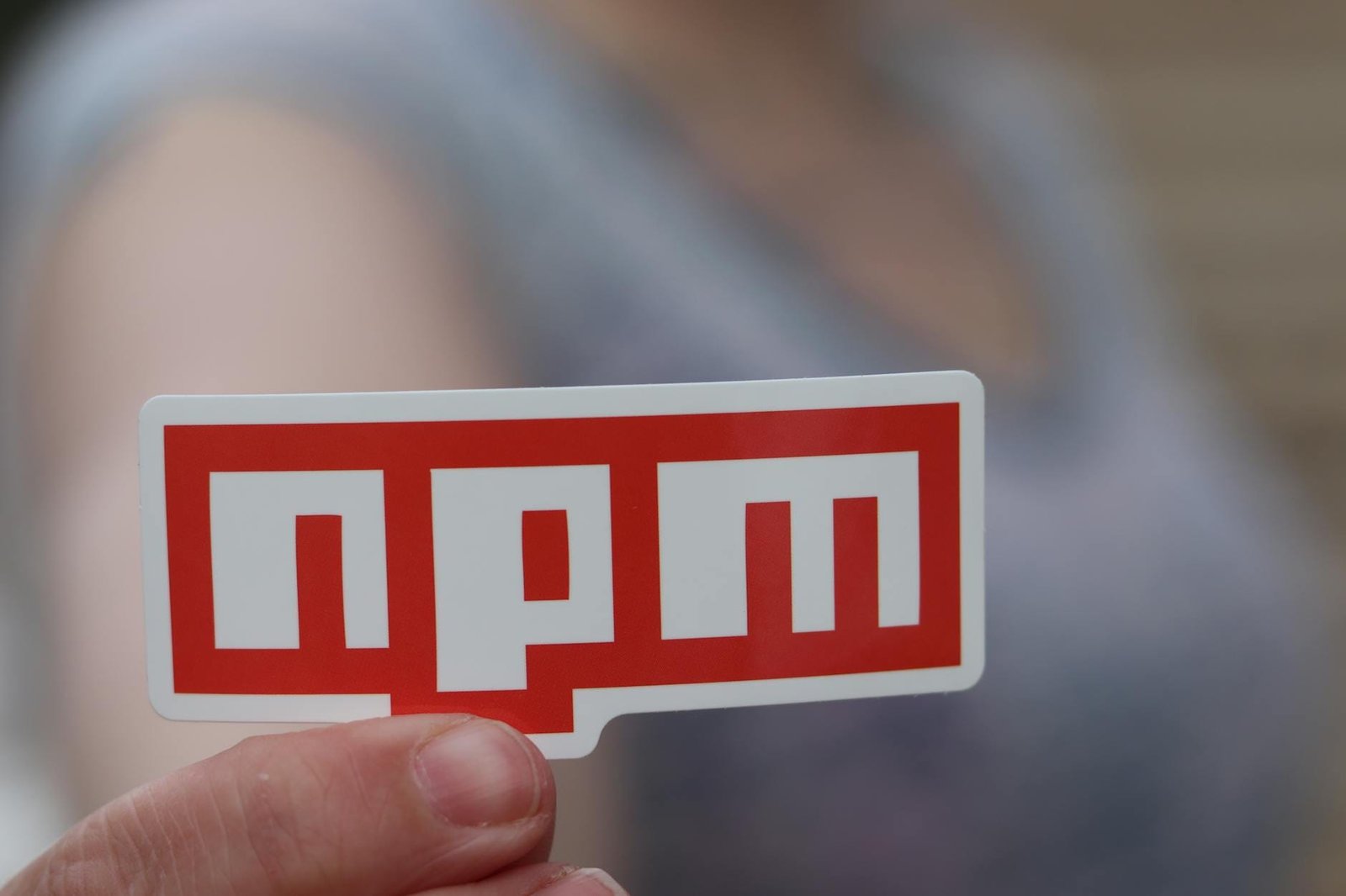 person holding a red npm sticker